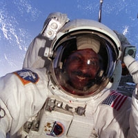 selfie of Winston Scott wearing a space suit with Earth behind him|