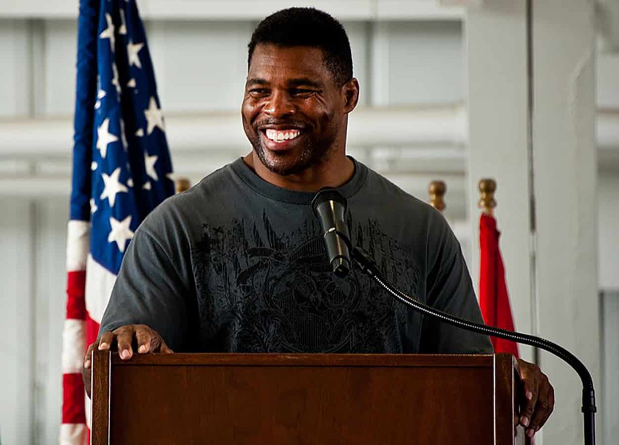 Herschel Walker smiling behind podium