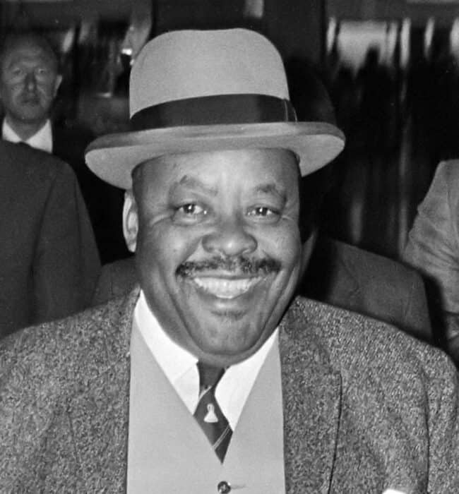 Jonathan of Lesotho smiling in brimmed hat and suit with vest and tie